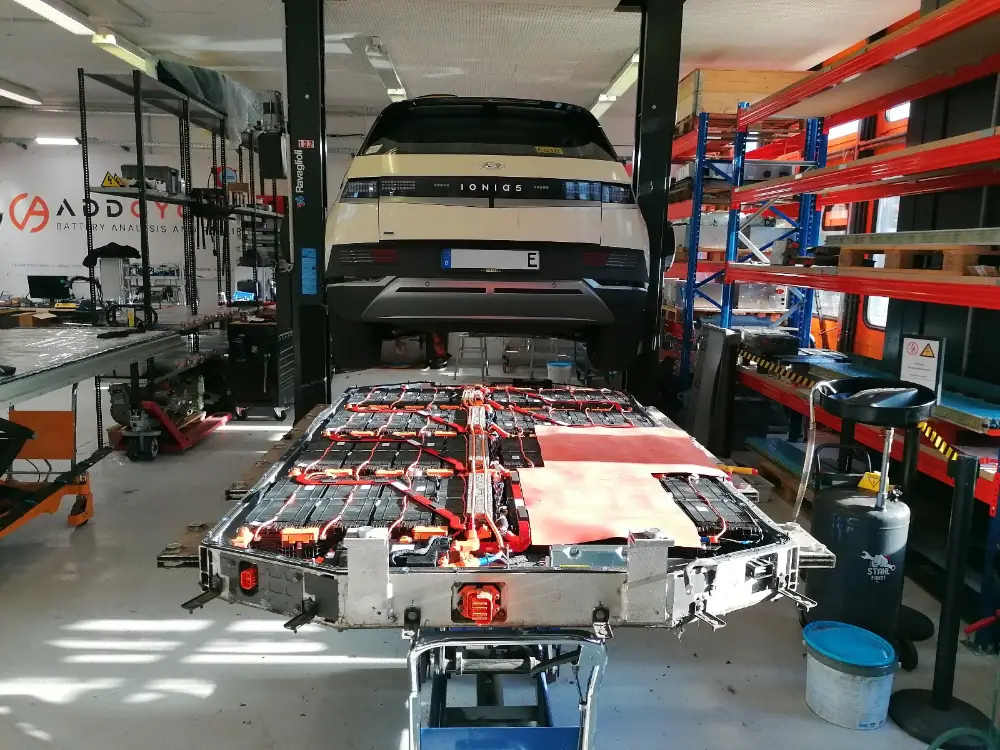 En Ioniq 5 på lift, under den den afmonterede batteripakke på et bord med modulerne synlige